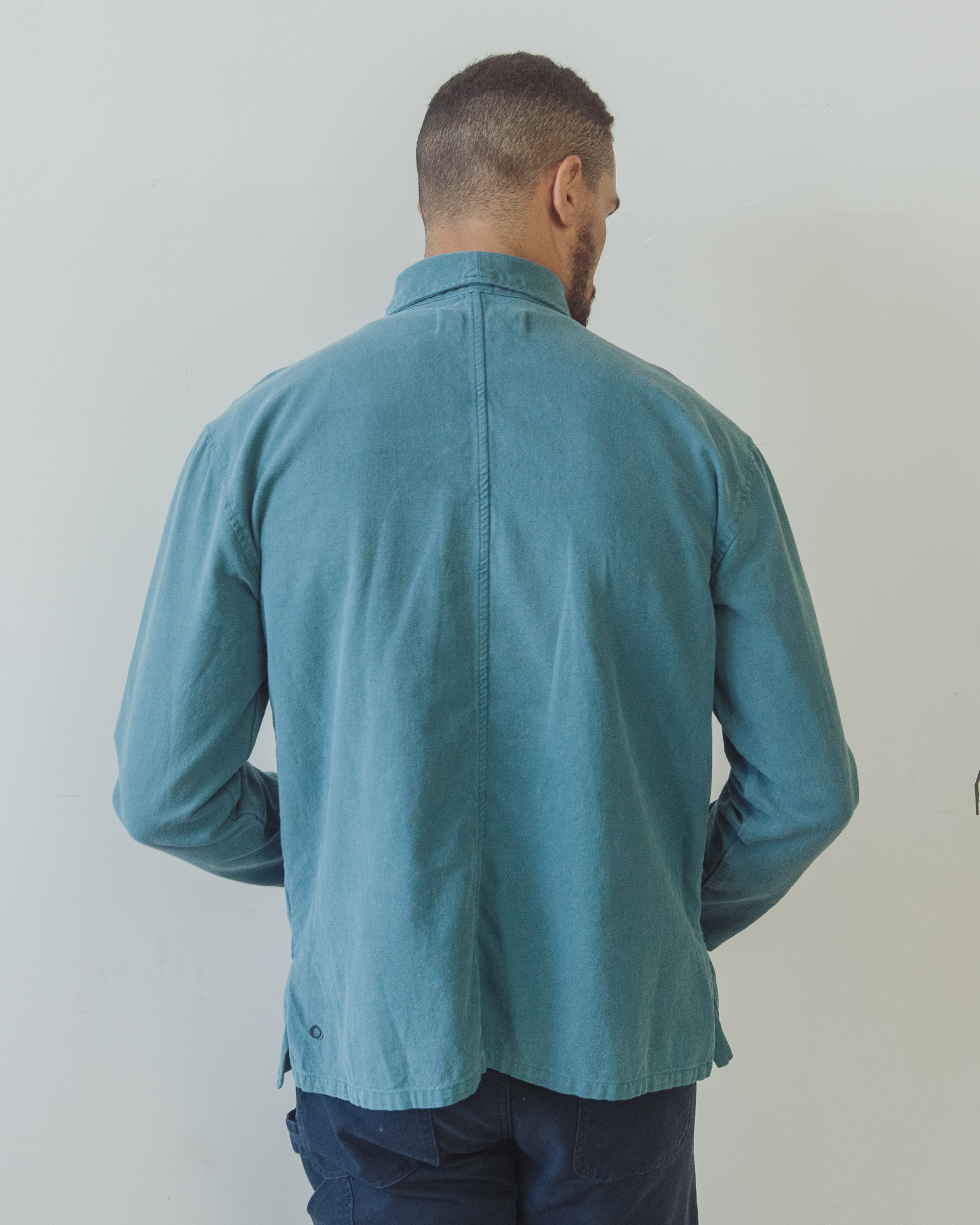 Man wearing a blue shirt against a plain background. Shepherds Shirt in Barracuda Blue Double Dipped Hemp Cloth.