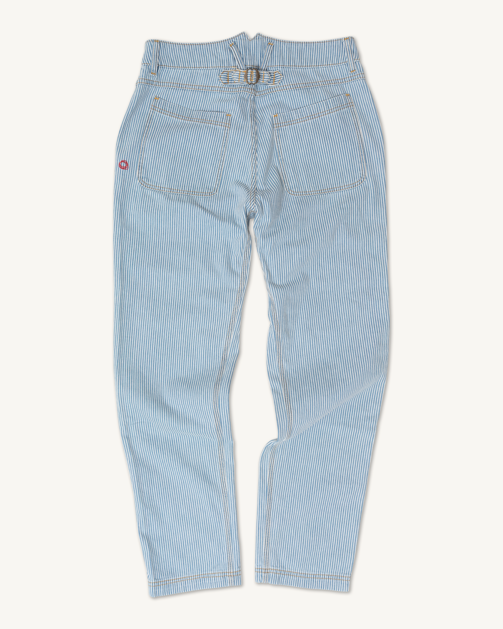 The Courier Pant Sharp Fit in Indigo Hickory Stripe by Imperfects is shown from the back with two rear pockets, a small red patch on the left, a buckle waistband strap, and straight legs, all on a white background. Vintage