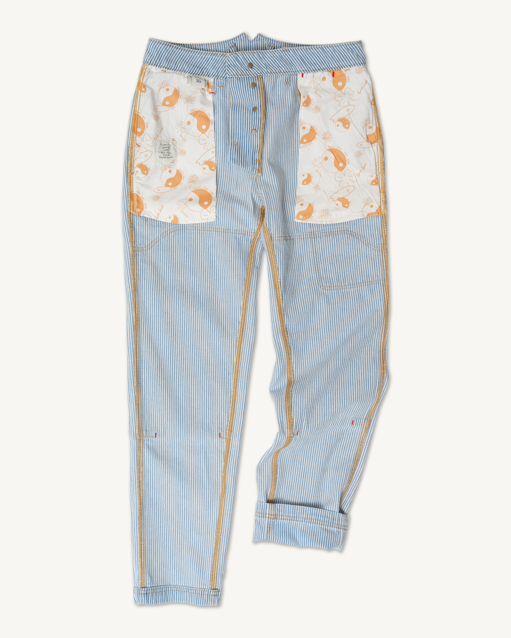 Imperfects' Courier Pant Sharp Fit in Indigo Hickory Stripe | Gold Thread Special features visible seams, gold contrasting stitching, two large front pockets with a white fox-and-leaf print, and rolled right leg cuff for classic workwear style.Vintage