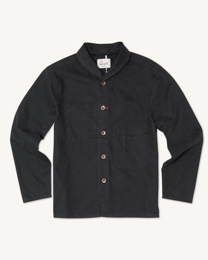 Flat lay of men’s Shepherd’s Shirt in Obsidian, made from organic cotton canvas, with a stand collar, five mismatched buttons, and a chest pocket.