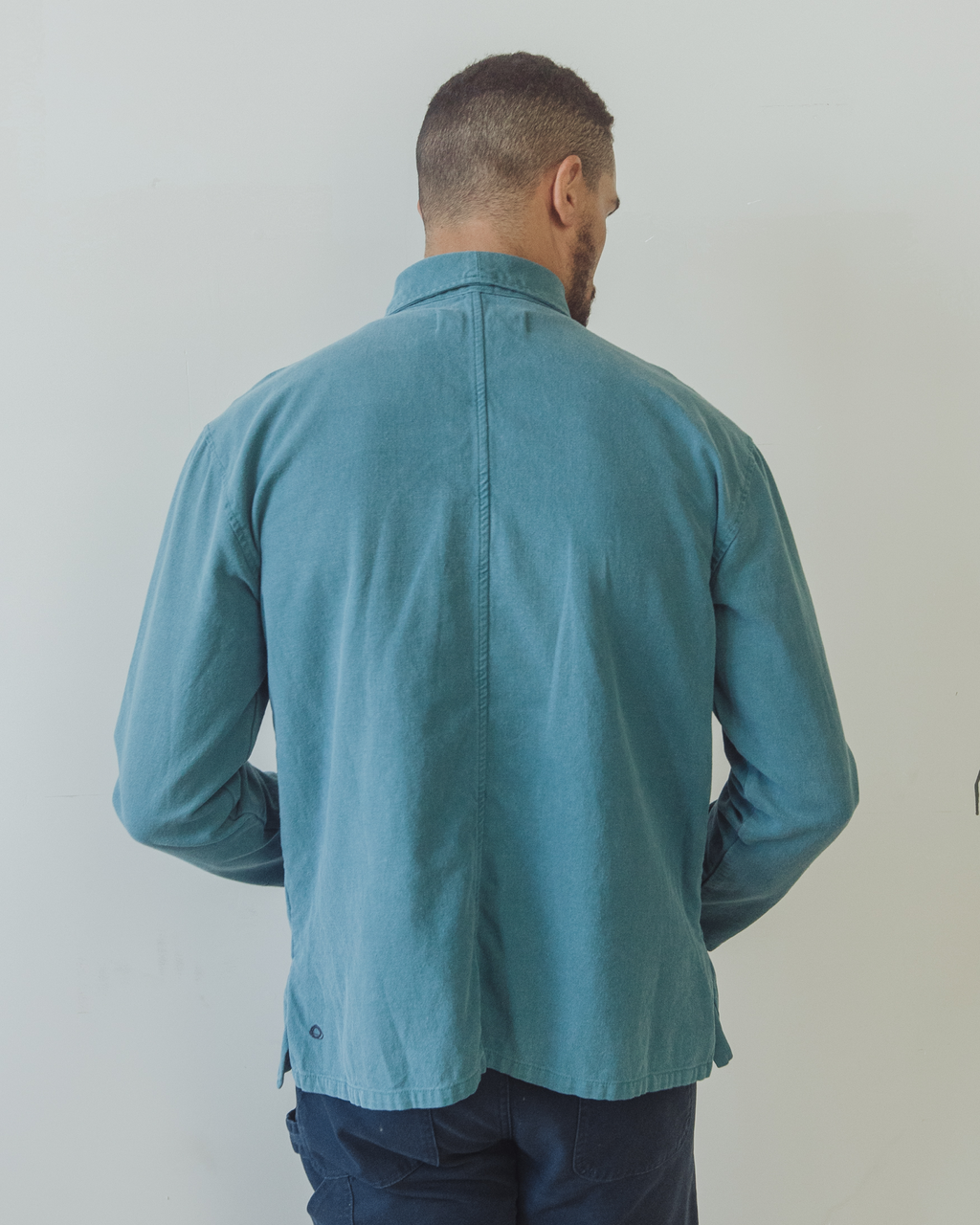 Man wearing a blue shirt against a plain background. Shepherds Shirt in Barracuda Blue Double Dipped Hemp Cloth.