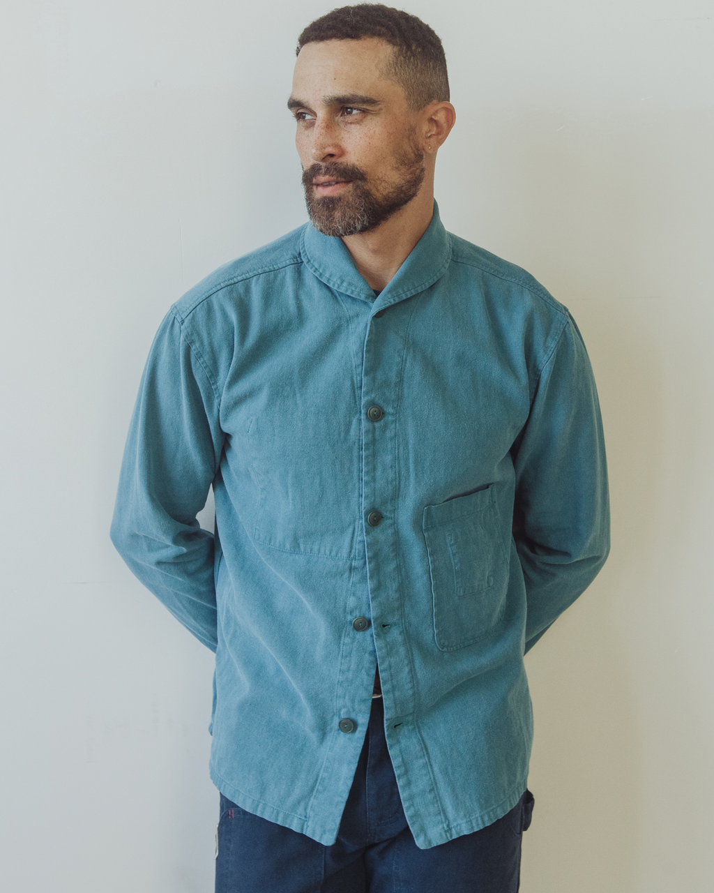Man wearing a teal jacket against a plain background. Shepherds Shirt in Barracuda Blue Double Dipped Hemp Cloth.